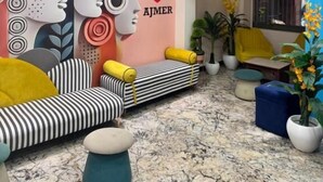 Un salon moderne avec un ventilateur de plafond, un canapé avec des coussins jaunes, un pouf bleu et une fresque murale.