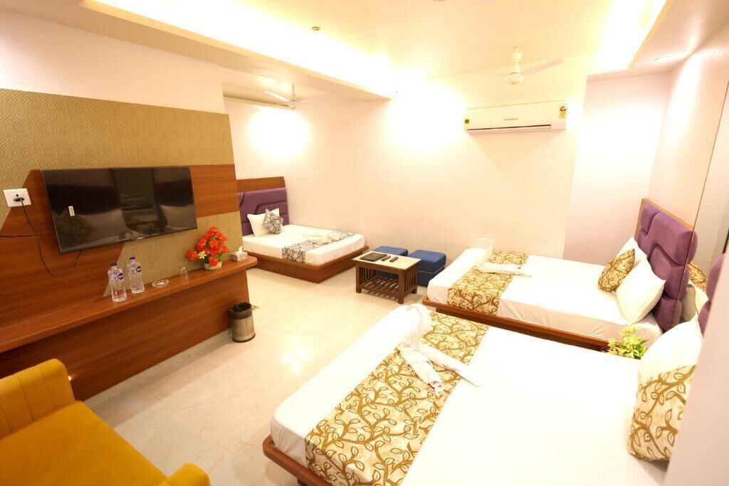 Habitación de hotel con dos camas, televisión, sofá, una mesita y un bote de basura.