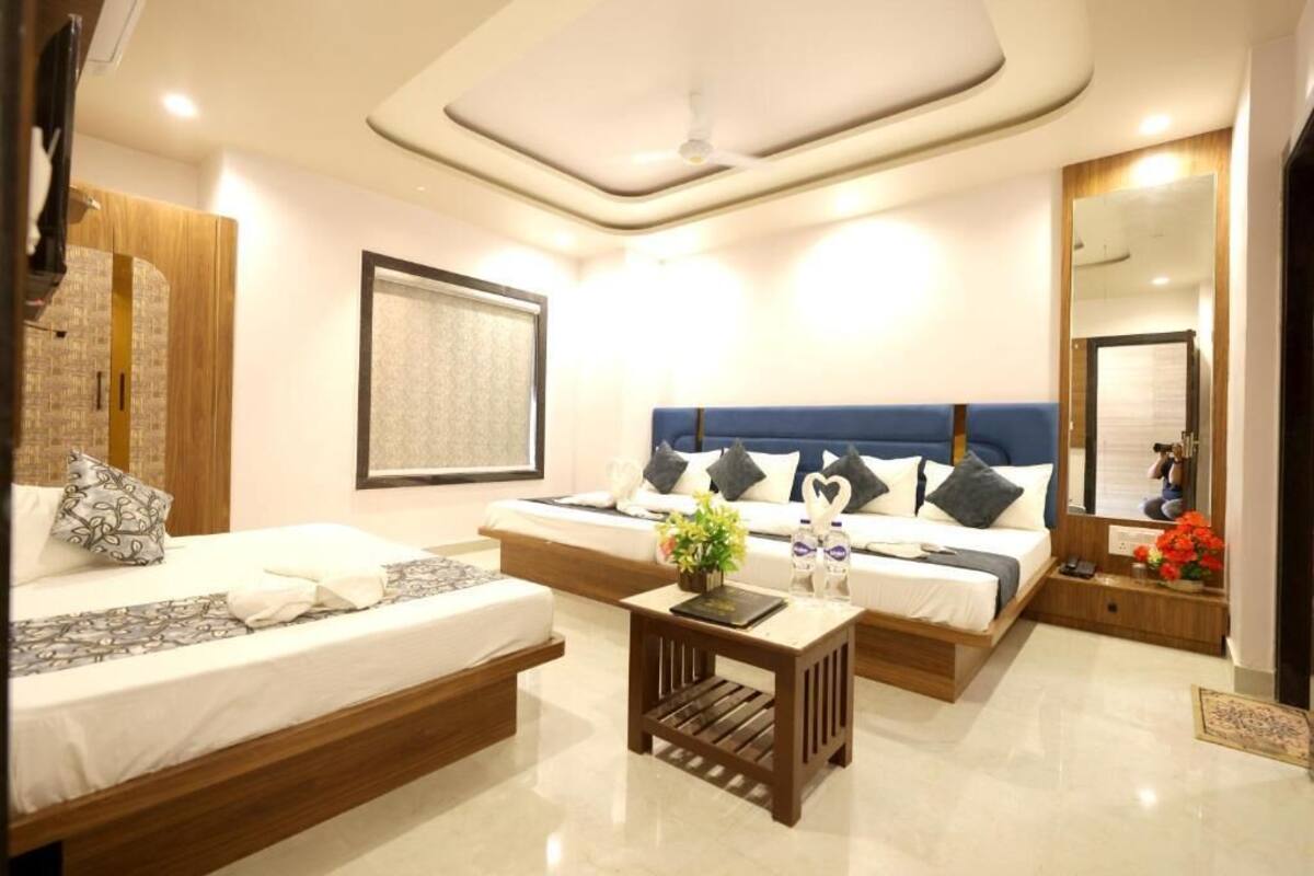 Una habitación de hotel moderna con cama, sofá, una mesita y un espejo.