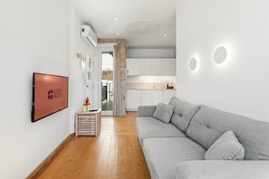 Ein modernes Wohnzimmer mit einem grauen Sofa, einem Flachbildfernseher und Holzboden.