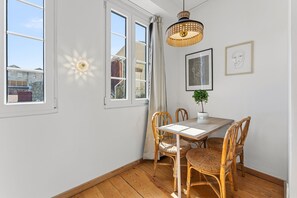 Ein Essbereich mit Tisch, Stühlen, einer Hängelampe und einem Fenster mit Vorhängen.