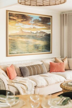 A living room with a sofa, pillows, a painting, and a coffee table. - Hidden Sunshine Beach Gem • Steps to the Beach! (Sunshine Beach)