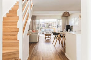A modern interior with a wooden staircase, a dining area with a table and chairs, and a sofa. - Hidden Sunshine Beach Gem • Steps to the Beach! (Sunshine Beach)