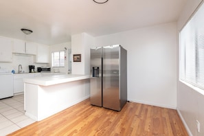Eine moderne Küche mit weißen Schränken, einem Edelstahl-Kühlschrank und Holzboden.