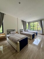 Camera da letto con due letti, un'ampia finestra e arredamento moderno.