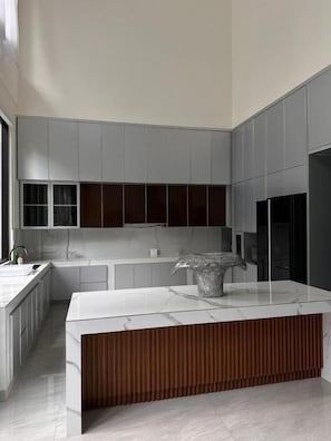 Una cucina moderna con mobili grigi, un piano di lavoro in marmo e un elemento decorativo in legno.