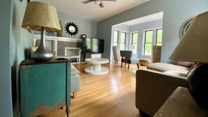 A living room with a fireplace, a television, a ceiling fan, and large windows. - Spacious 3 bedroo, large livingroom and dining room. (Chicago)