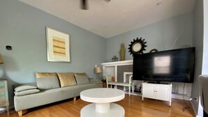 A living room with a sofa, a round white table, a television, and a fireplace. - Spacious 3 bedroo, large livingroom and dining room. (Chicago)