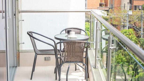 A balcony with a glass railing, a table, and two chairs.