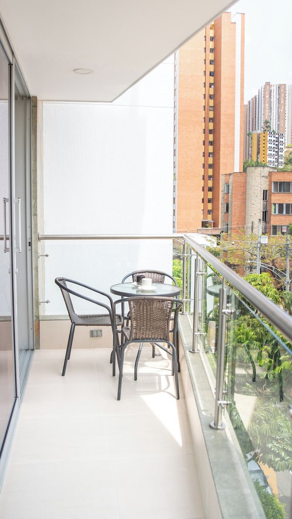 Ein Balkon mit Glasgeländer, einem Tisch und zwei Stühlen.