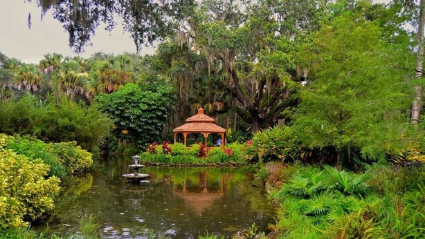 Ein friedlicher Garten mit einem Pavillon, Teich und üppiger Vegetation.