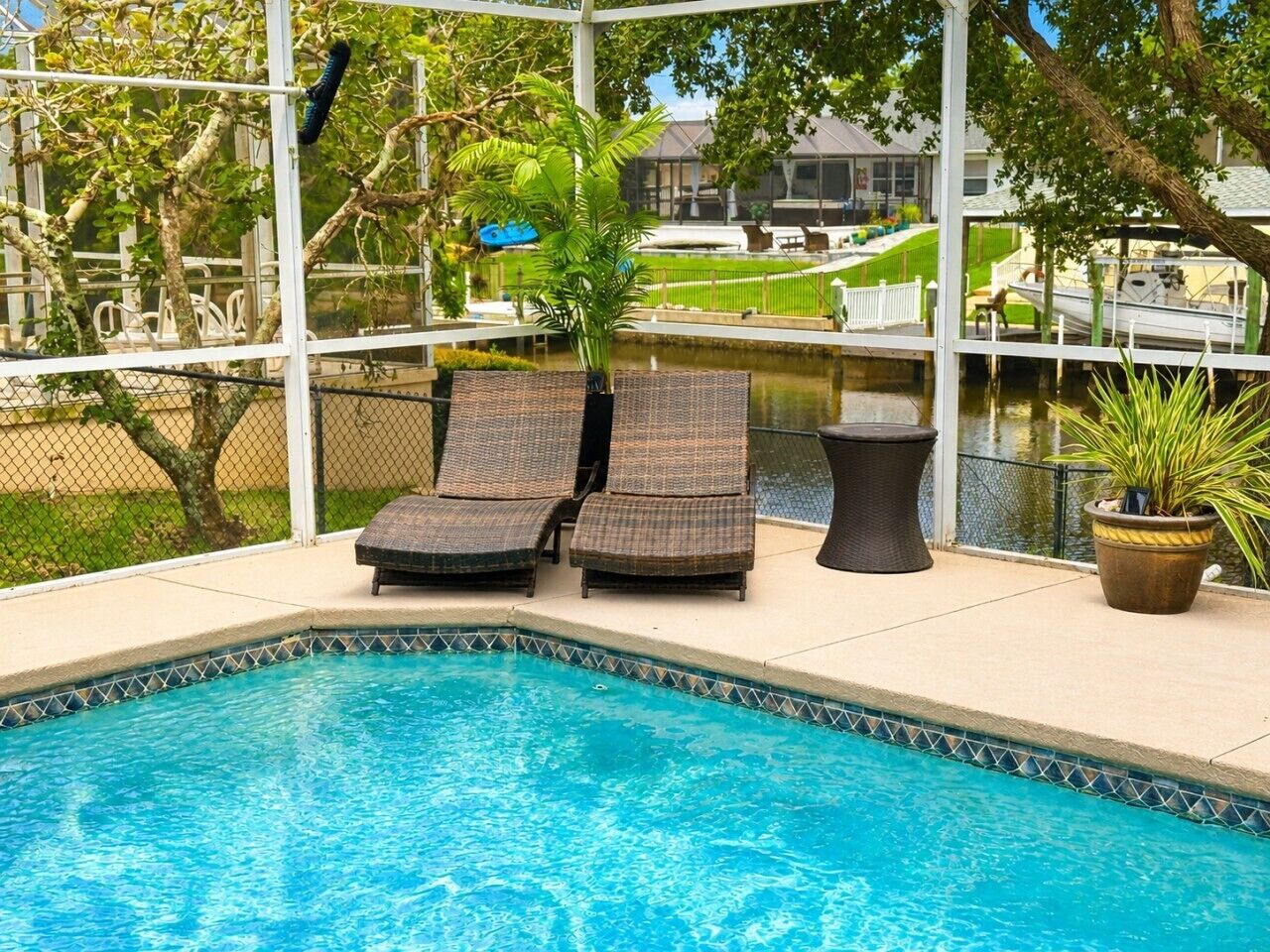 A swimming pool with lounge chairs and a potted plant.