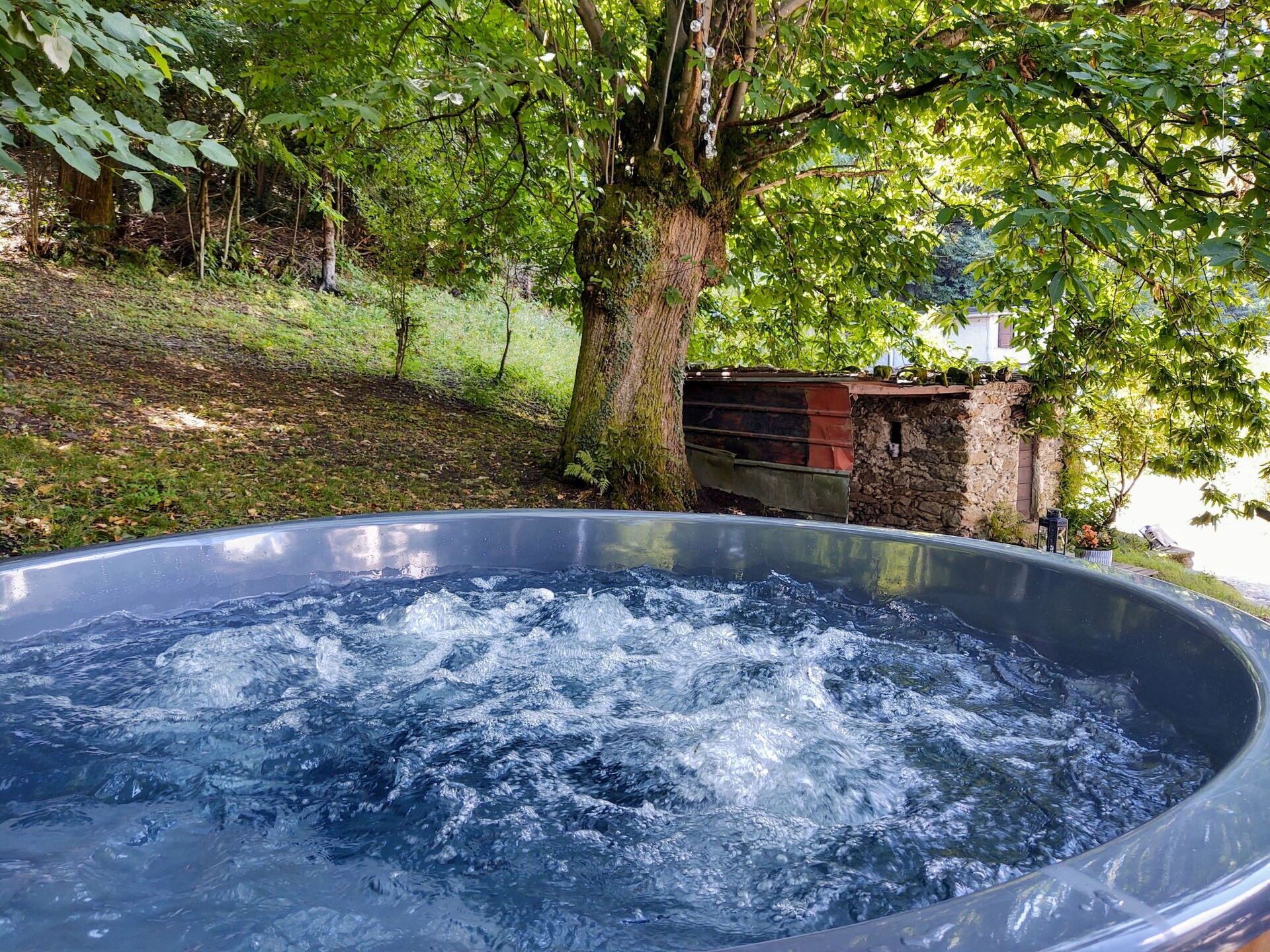 A hot tub surrounded by trees and a stone wall.