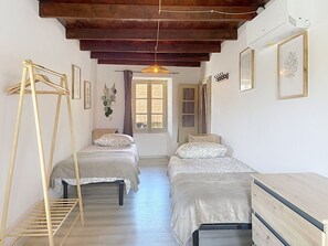 Ein Zimmer mit zwei Betten, einer Holzleiter, einer Hängeleuchte und einer zur Außenseite führenden Tür.