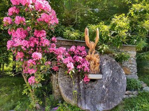 Ein Garten mit einem großen Felsen und einer Holzskulptur eines Adlers.