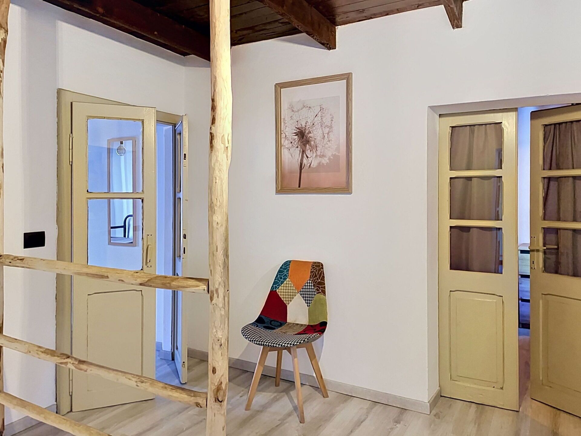 A room with a wooden chair, a framed picture on the wall, and a door with curtains.