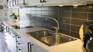 Eine moderne Küche mit einem doppelten Spülbecken, Edelstahlgeräten und einer schwarzen Küchenrückwand.