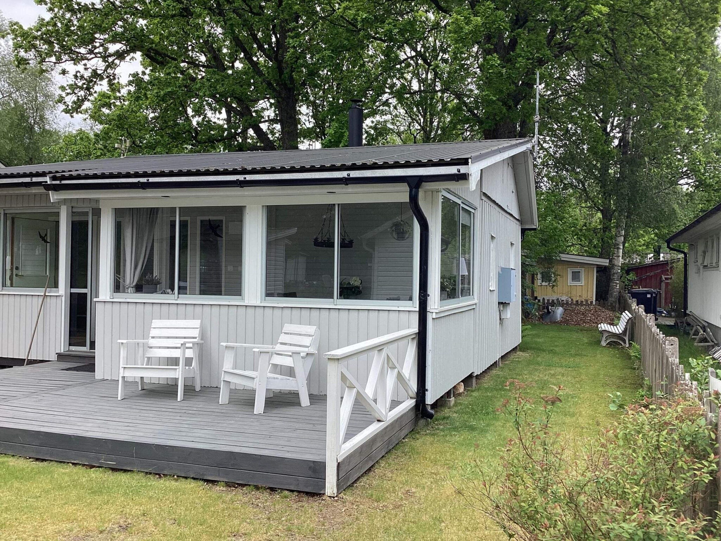 A single-story house with a covered porch, a dining table with chairs, and a small deck.