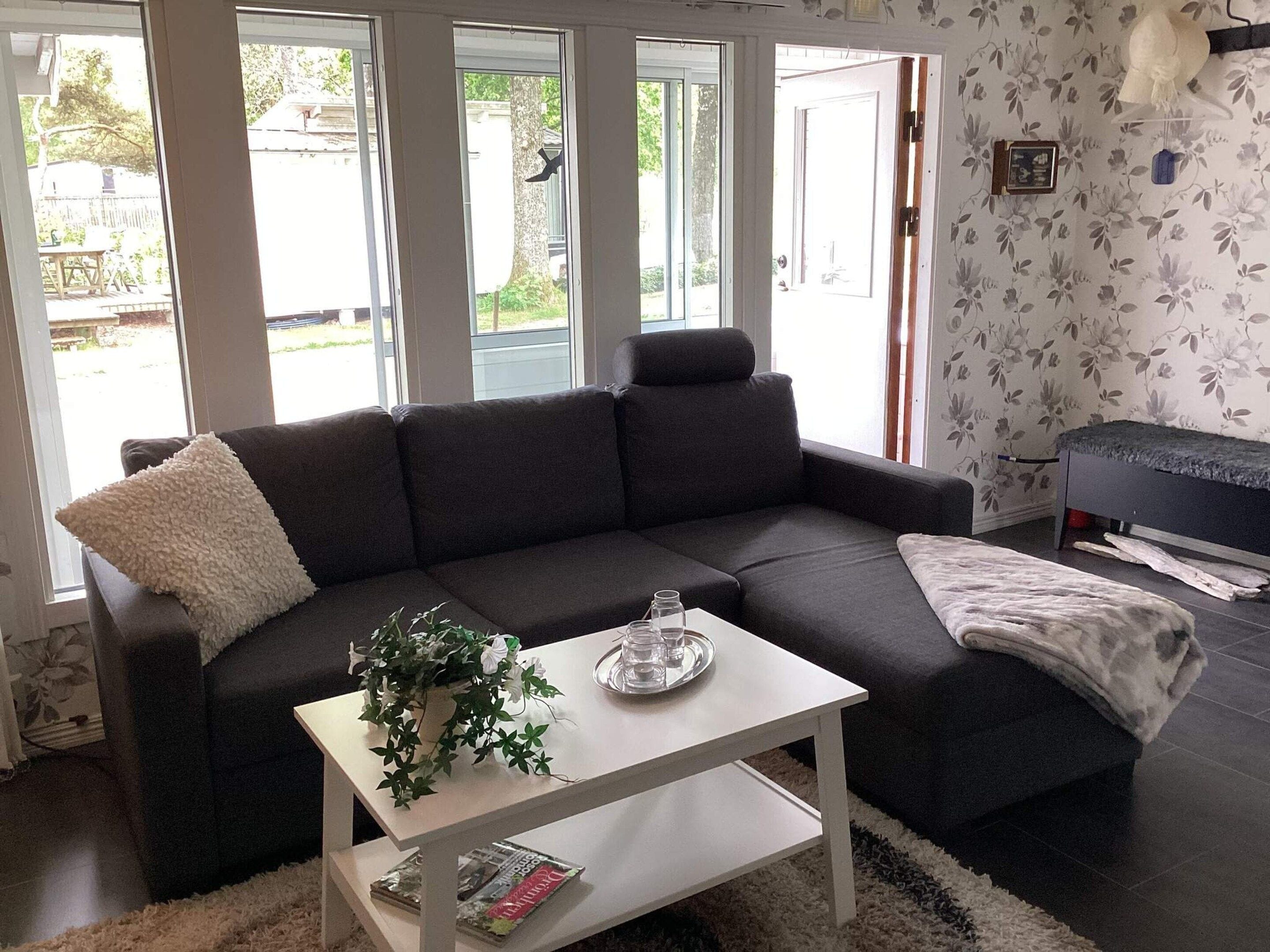 Ein modernes Wohnzimmer mit einem dunkelgrauen Ecksofa, einem weißen Couchtisch und einem kleinen Beistelltisch.