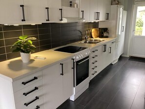 A modern kitchen with white cabinetry, a black countertop, a stove, an oven, and a sink. - 4 Star Holiday Home in Hyltebruk (Hyltebruk)