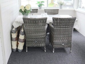 A dining area with wicker chairs, a table, and a vase of flowers. - 4 Star Holiday Home in Hyltebruk (Hyltebruk)