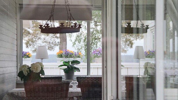 Eine Veranda mit Korbmöbeln, einem Topfpflanzen und hängenden Kronleuchtern.