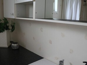 A bathroom with a white countertop, a sink, a mirror, and a potted plant. - 4 Star Holiday Home in Hyltebruk (Hyltebruk)