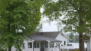 Ein eingeschossiges weißes Haus mit Veranda, kleiner Terrasse und umzäunter Garten.