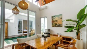 A spacious dining area with a wooden table and chairs, a large potted plant, and a painting on the wall. - Family 2 Bedroom Villa by Seminyak - B13 (Kota Denpasar)