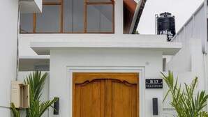 A modern building with a large wooden double door, a sign reading 'B13 Villaginger,' and potted plants on either side. - Family 2 Bedroom Villa by Seminyak - B13 (Kota Denpasar)