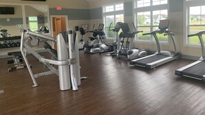 Ett gym med konditionsmaskiner, styrketräningsmaskiner och en spegel.