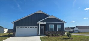 Un immeuble résidentiel à deux étages, doté d’un garage, de fondations en pierre et surplombant un ciel d’un bleu éclatant.