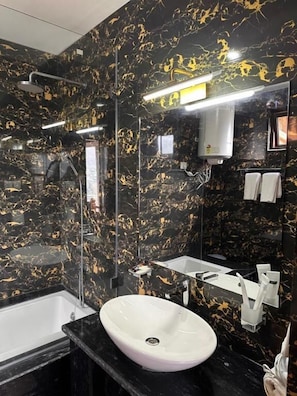 A bathroom with a white sink, black marble walls, and a large mirror.