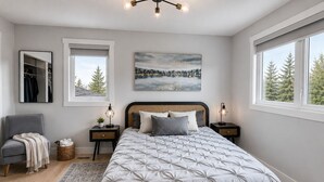 A bedroom with a bed, bedside tables, a chair, a rug, a mirror, and a painting.