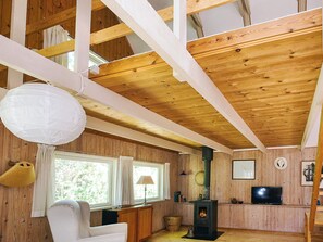 A cozy cabin interior with wooden beams, a fireplace, a television, and a comfortable seating area. - 4 Star Holiday Home in Sejero (Sejero)