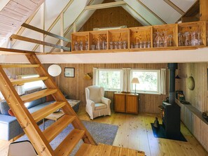 Un dormitorio tipo loft con escalera de madera, una silla, una mesita y una chimenea.