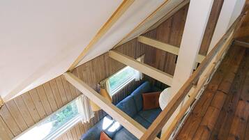 Un espacio tipo loft con techo de madera, un sofá azul y un ventanal.