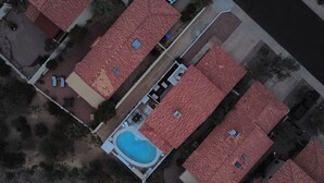 An aerial view of a residential area with multiple houses, a swimming pool, and a clear sky.
