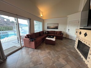 A living room with a sectional sofa, a fireplace, and a view of a pool. - Arrowzona Mountain Home - Phoenix (Phoenix)