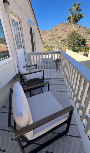 Ein Balkon mit weißer Brüstung, einer Couch und einem kleinen Tisch.