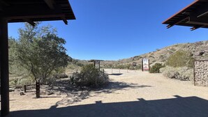 A desert landscape with a dirt path leading to a building with a metal roof.