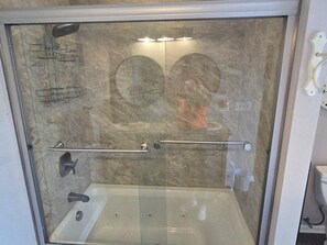 Een glazen douchecabine met een marmeren wand, een handdoekrek en een handgreep.