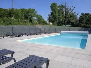 A swimming pool with lounge chairs, a fenced area, and trees in the background. - Olydea le Domaine du Lambon (Prailles-la-Couarde)