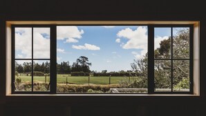 Een raam met uitzicht op een landelijk landschap, met velden en bomen.