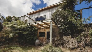 Een houten huis met een balkon, omringd door weelderige begroeiing en een heldere lucht.
