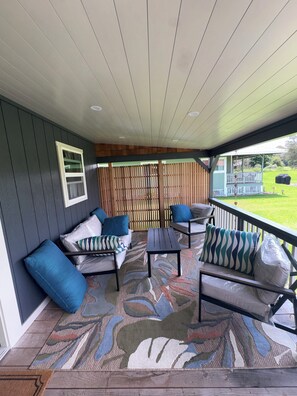 A covered patio with a sofa set, a table, and a patterned rug.