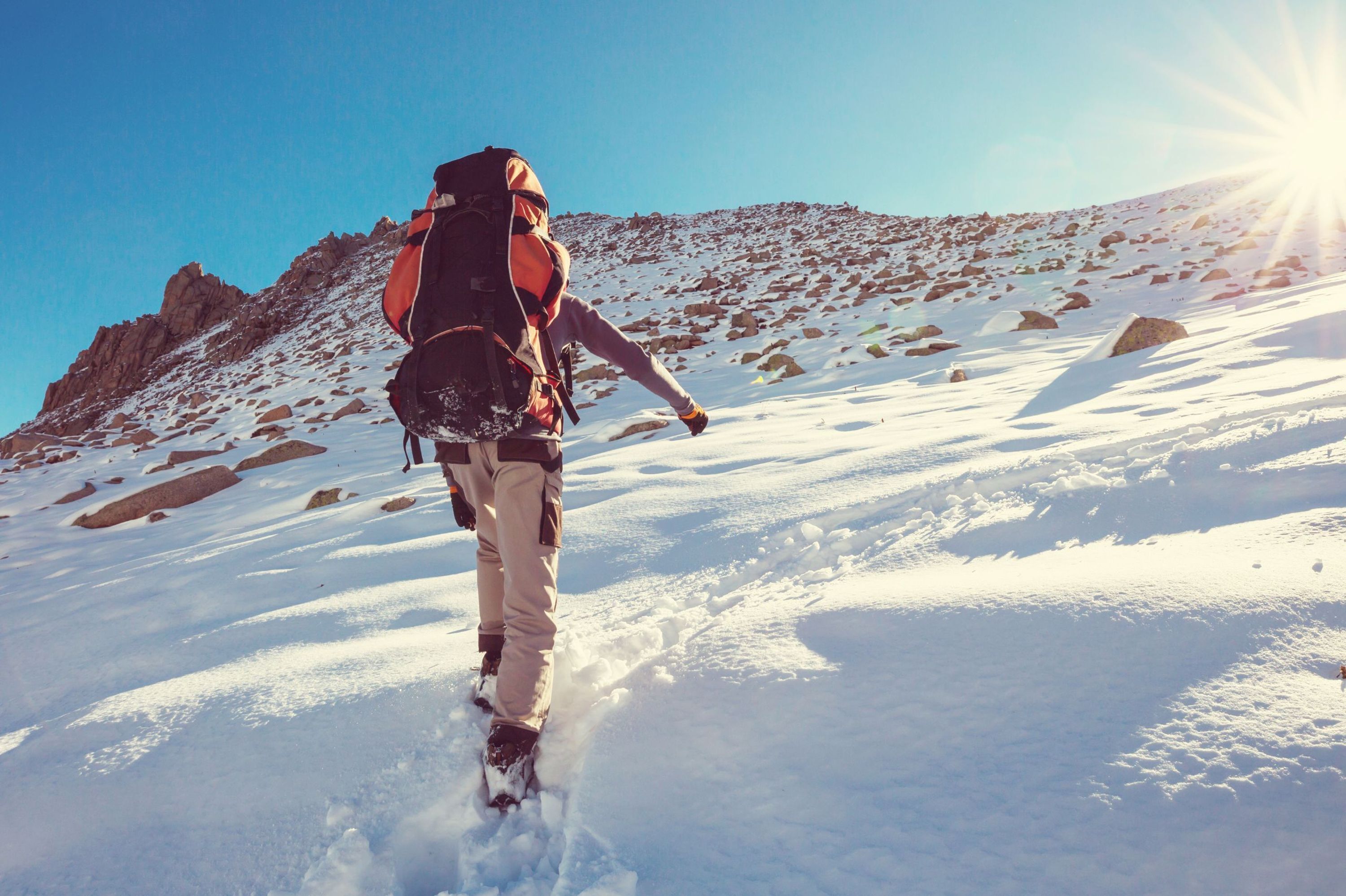 A person hiking in a snowy mountainous area with a backpack.