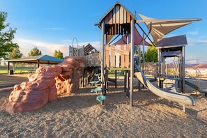 Ein Spielplatz mit Rutsche, Klettergeräten und einer Felsformation.