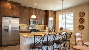 A kitchen with dark wooden cabinets, stainless steel appliances, a granite countertop, and pendant lighting. - Paradise Village Modern Retreat w/ Hot Tub & Pool (Santa Clara)