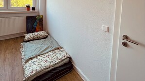 Una stanza con finestra, termosifone, letto e porta.